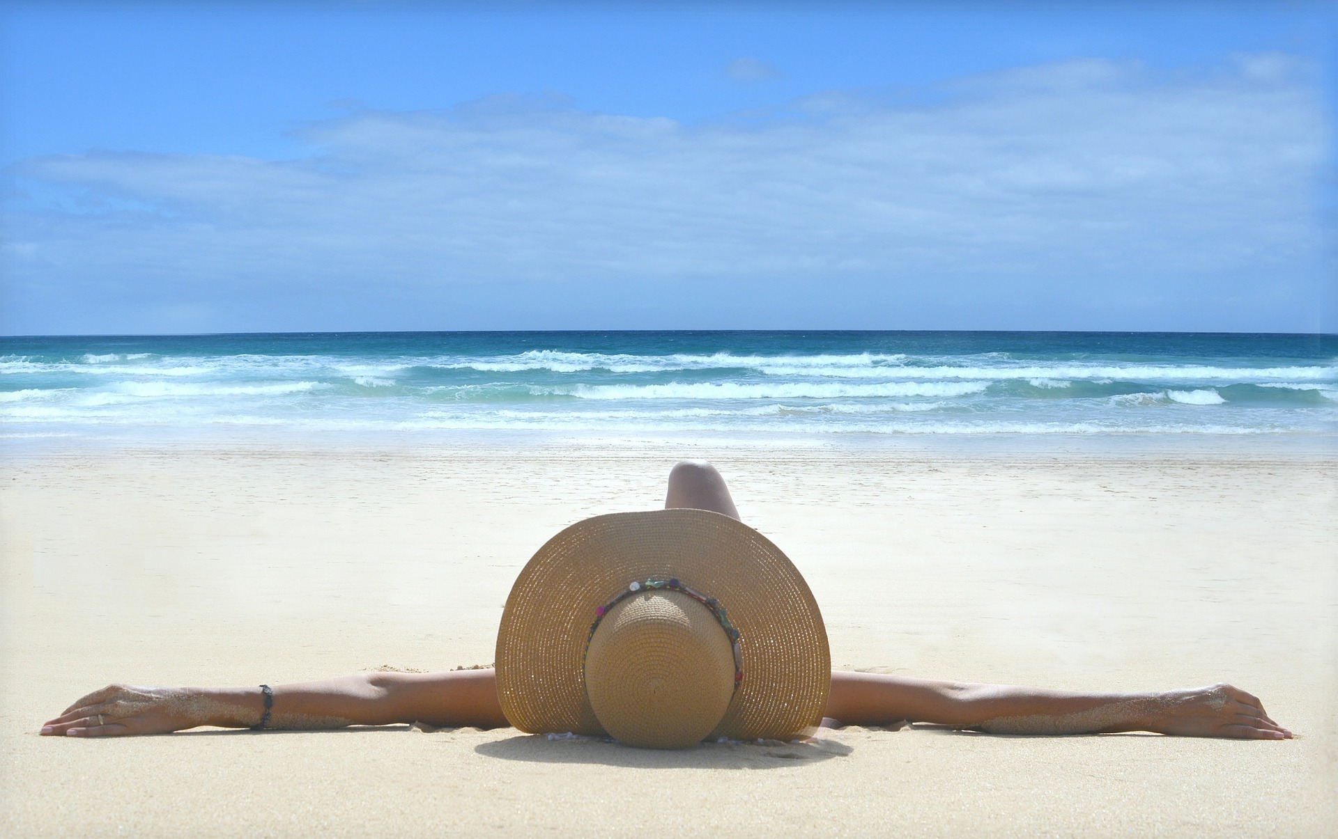 Woman in hat tanning on the beach