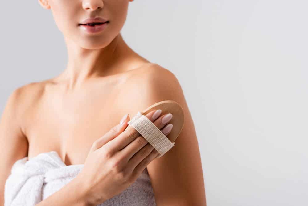 Woman exfoliating her skin before applying self tanner