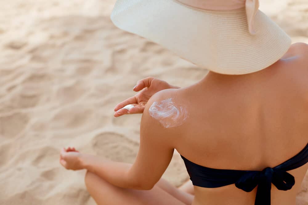 A woman applying sunscreen to her skin before using a sunless tanner