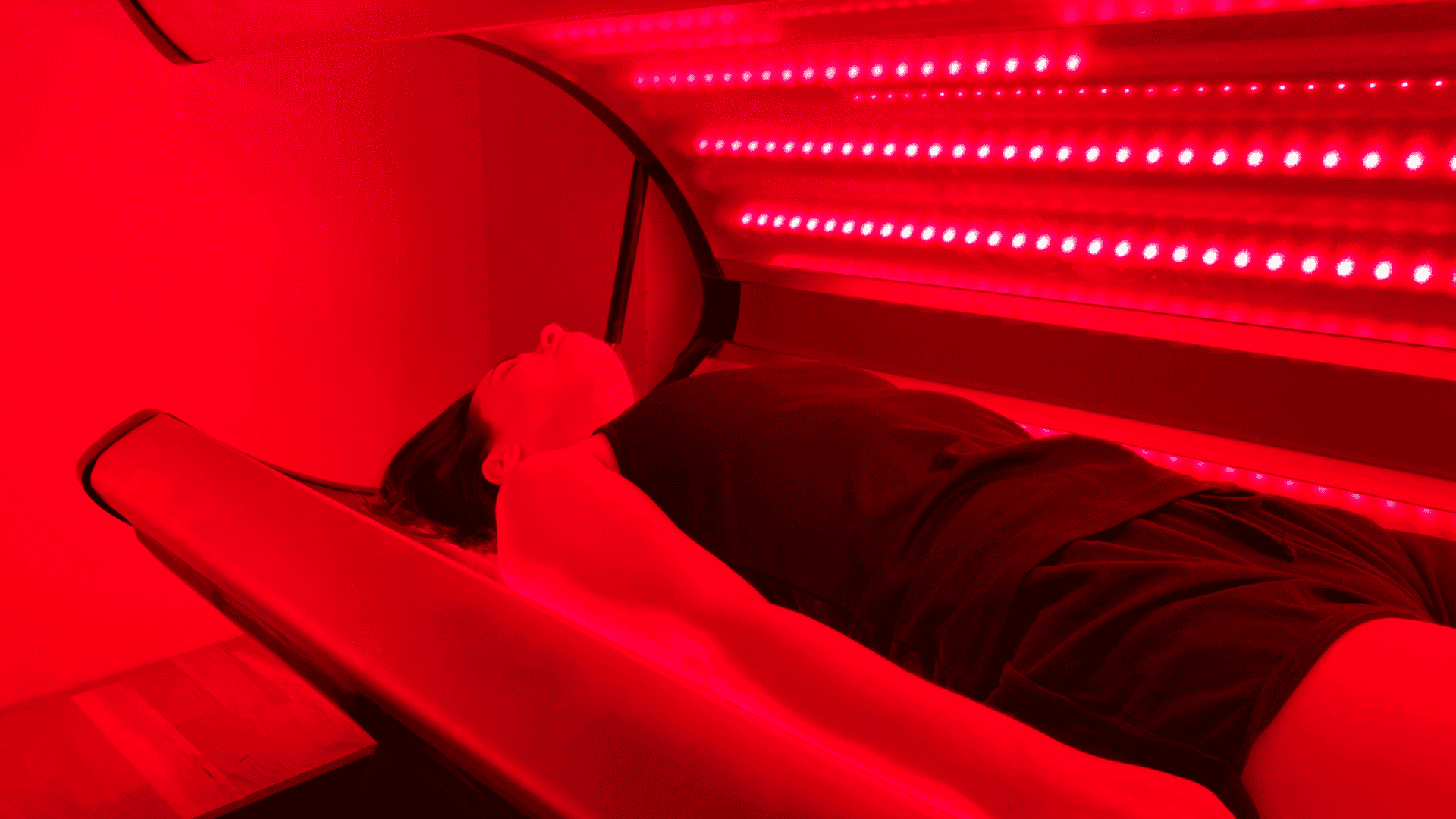 A person lying on a red light therapy bed